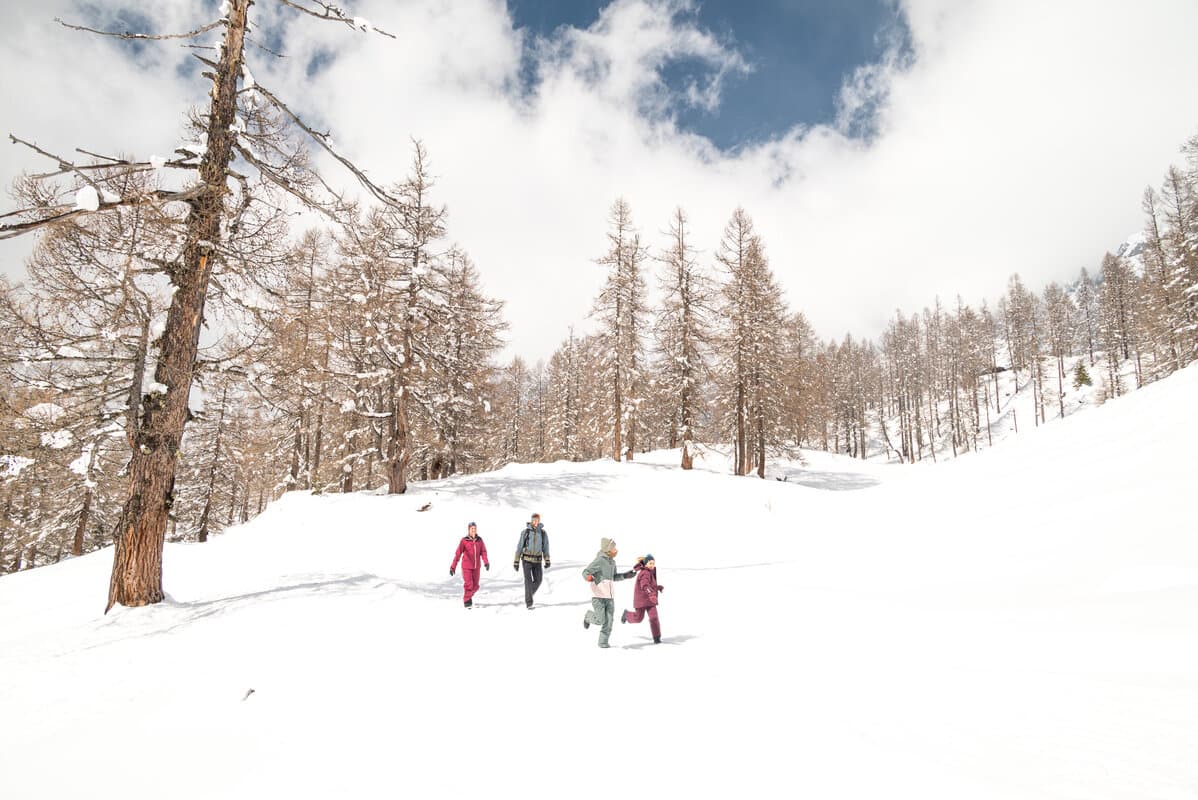 Familie läuft durch die verschneite Winterlandschaft